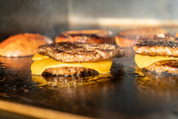 Make burgers on the grill restaurant. Burgers cooking on a gas grill, how to make a burger step by step. A person using a spatula to cut meat. a person cutting meat on a grill with a knife
