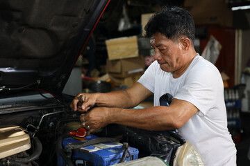 Man technician car mechanic in half uniform checking maintenance a car service at repair garage station. Worker holding wrench and fixing breakdown vehicle. Concept of car center repair service.