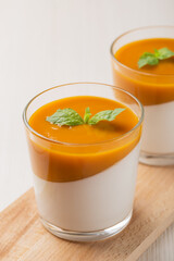 Close up c vegan coconut Panna cotta with mango sauce in glasses on white wooden table. Healthy food. Vegan dessert. Vertical orientation.