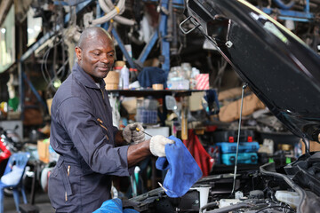 Man technician car mechanic in uniform checking maintenance a car service at repair garage station. Worker checking motor oil level in car engine. Concept of car center repair service.