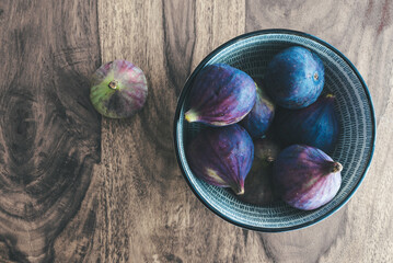 top down view of fresh figs in bowl on wooden table.