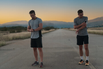 Sport couple looking at a smartwatch while standing on the country road. Resting after jogging and running exercise and checking heart rate and pulse.