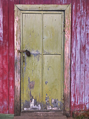 Old door with a lock, entrance to an old wooden red house