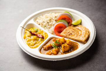 Indian mini meal parcel platter or combo thali with Gobi Masala, roti, dal tarka, jeera rice, salad