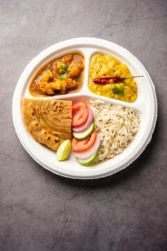 Indian mini meal parcel platter or combo thali with Gobi Masala, roti, dal tarka, jeera rice, salad
