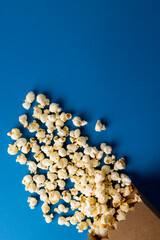 Vertical image of pop corn scattered on blue surface
