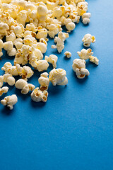 Vertical image of pop corn scattered on blue surface