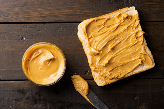 Image of bowl and bread slice with peanut butter on wooden surface