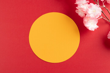 Composition of close up of cherry blossom and yellow circle on red background