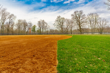 View of typical nondescript high school softball field with clay infield from first base side of...