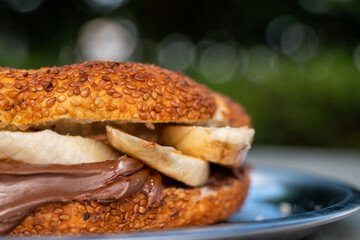A sandwich with chocolate spread and banana. Bagel, simit, bread with bananas and chocolate cream on. tasty sweet breakfast or lunch sandwich with hazelnut chocolate spread and fresh banana slices