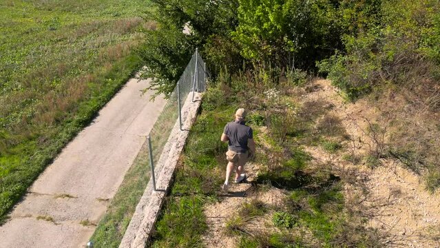Un homme marche dans un parc suivi par un drone
