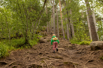 Obraz premium Child in yellow jacket looking down from Rampestreken in Andalsnes. Norway
