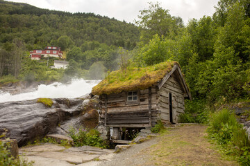 Amazing little wooden small house next to a waterfall on the dock of Hellesylt, child playing in...