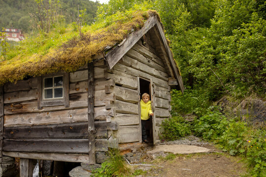 Amazing little wooden small house next to a waterfall on the dock of Hellesylt, child playing in the house