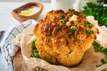 Baked cauliflower. Oven or whole baked cauliflower spices and herbs server on wooden rustic board...