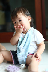 A cute baby is sitting and using her hand to eat rice in natural light.