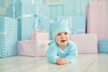 A baby lies on a soft surface in a bright room, dressed in dark-colored clothing. The concept of childhood