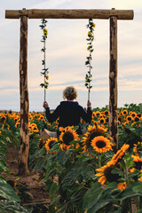 woman on swing in sunflower field
