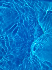 Defocus blurred transparent blue colored clear calm water surface texture with splashes and bubbles. Trendy abstract nature background. Water waves in sunlight with copy space. Blue watercolor shining