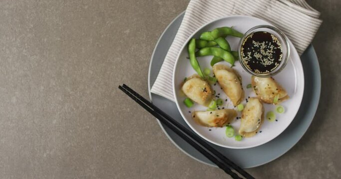 Composition of plate with gyoza dumplings and soy sauce with chopsticks on grey background