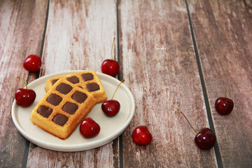 sweet baked fluted Belgian waffles with chocolate filling and red cherries on a ceramic plate