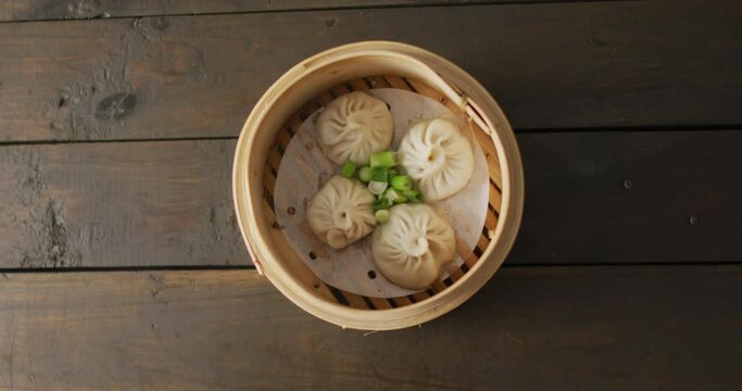 Composition of bamboo steamer with dim sum dumplings on wooden background