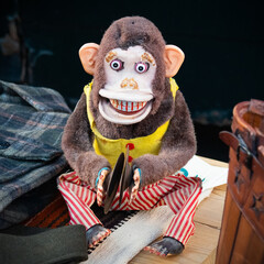 Retro toy monkey with cymbals, jolly chimp, on wooden counter with clothes 