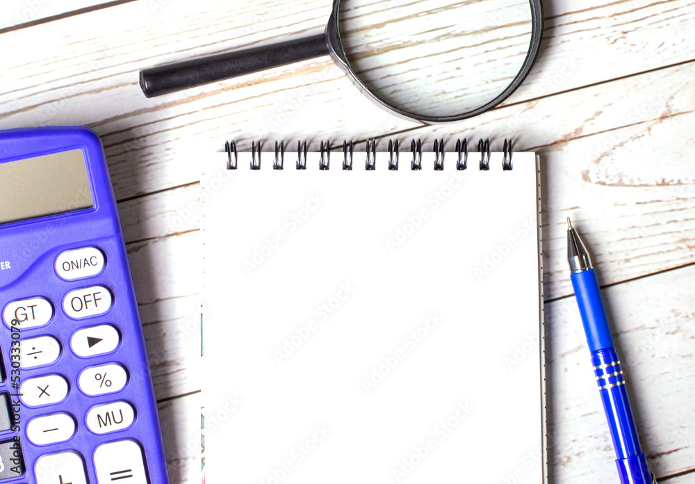 Poster top view of work desk with magnifying glass, blue calculator, pen and blank notepad with space to in