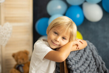 Fototapeta na wymiar Cute preschool boy, playing with airplane, balloons and birthday decoration