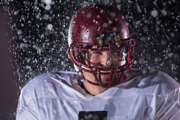 American Football Field: Lonely Athlete Warrior Standing on a Field Holds his Helmet and Ready to Play. Player Preparing to Run, Attack and Score Touchdown. Rainy Night with Dramatic Fog, Blue Light