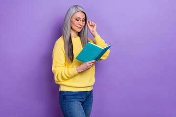 Photo of clever pretty lady pensioner dressed pullover arms eyewear reading fiction literature isolated purple color background