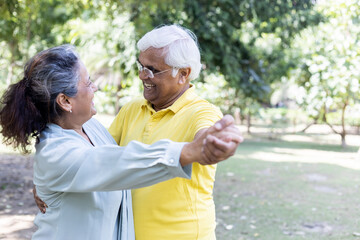 Cheerful active senior couple in public park together having fun.