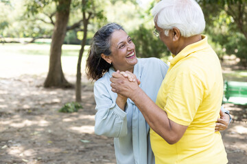 Cheerful active senior couple in public park together having fun.