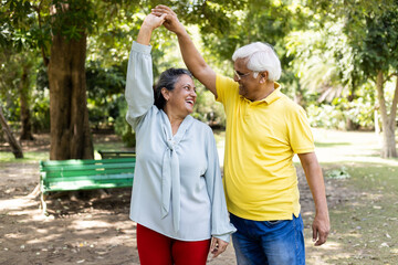 Cheerful active senior couple in public park together having fun.
