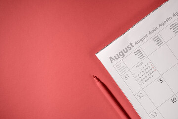 close-up of calendar and red pencil on red table background, business meeting planning or travel planning concept