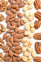 Top view of different delicious nuts on white background. Space for text. Nuts background. Vertical photo