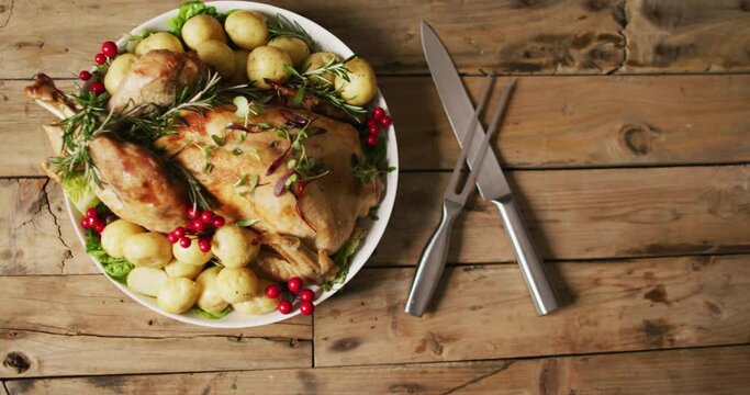 Video of tray with roasted turkey, potatoes and cutlery on wooden surface