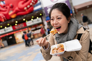closeup portrait of a happy Asian Japanese woman holding a box of takoyaki octopus balls while...