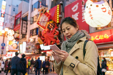 Asian Japanese girl tourist looking at online restaurant reviews on phone while deciding what to...