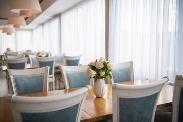 Elegant luxury interior in white colors. Beautiful vintage decoration for wedding, birthday, party or restaurant table set. Decoration with flowers in vase. Natural light.