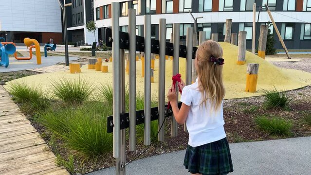 little girl hitting notes on tubular bells with two hammers