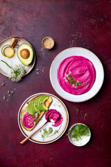 Avocado toast with pink beet hummus spread or dip with edible onion flowers and microgreens. Healthy plant based appetizer, vegan, vegetarian snack