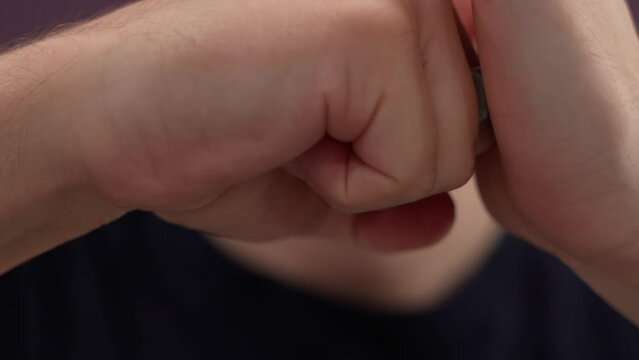 brass knuckles in a man's hand. menace. agressive.