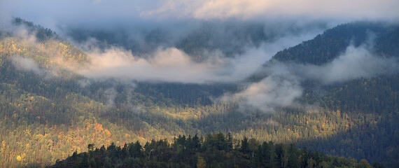 Dawn in the mountains, fog and clouds on the peaks, panoramic