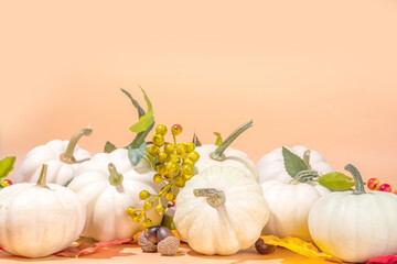 Obraz na płótnie Canvas Autumn decorative pumpkins with fall leaves on beige background. Fall Thanksgiving halloween holiday greeting card background, harvest concept. Top view, copy space
