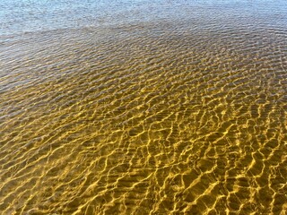 Transparent sea water ripples, sandy bottom, natural background