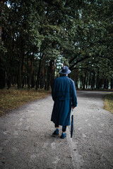 young english man in stylish vintage coat and black hat walking in rainy forest