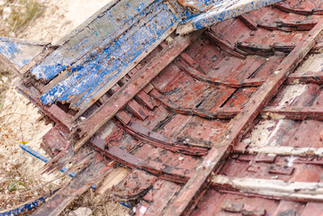 Remains of an old wooden boat. The bow of the wooden boat is stuck in the coastal rocks.