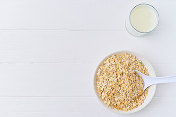 bowl of granola with a spoon and a glass of oat milk. white wooden background. top view. copy space.